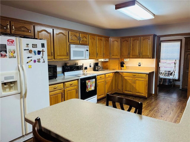 kitchen featuring dark wood-type flooring, white appliances, light countertops, and brown cabinets