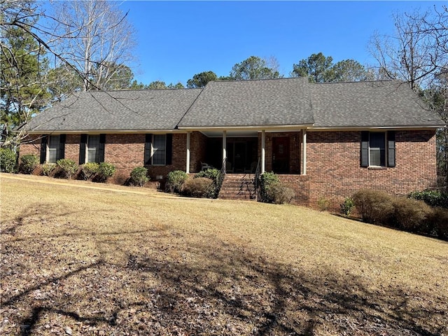 single story home with a shingled roof, brick siding, and a front lawn