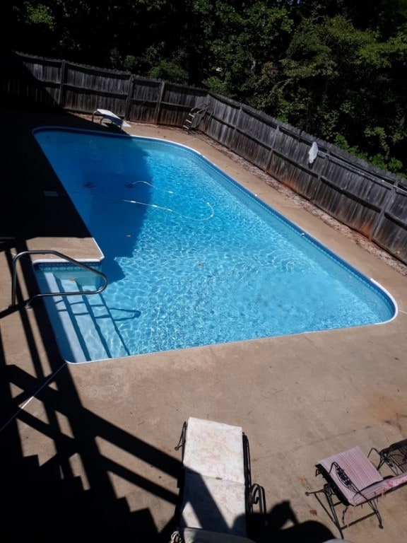 view of swimming pool with a diving board, a fenced backyard, and a fenced in pool