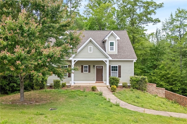 cape cod home with a front lawn, a shingled roof, and covered porch