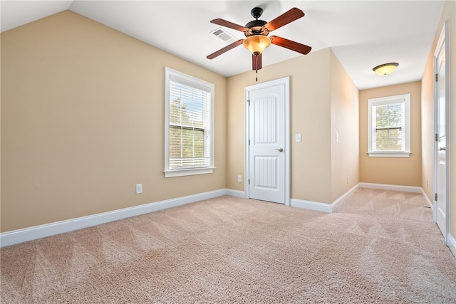 unfurnished bedroom featuring multiple windows, visible vents, baseboards, and light carpet