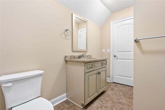 bathroom featuring toilet, vanity, vaulted ceiling, and baseboards