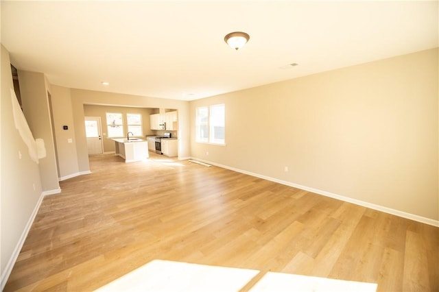 unfurnished living room featuring light wood-type flooring and sink