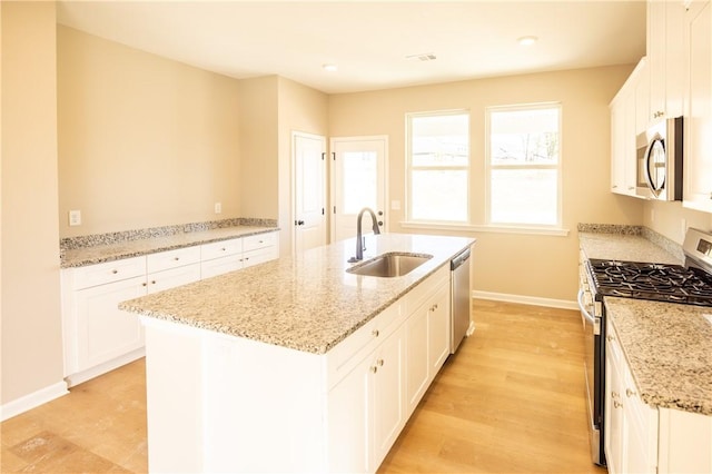 kitchen with a center island with sink, white cabinets, sink, and stainless steel appliances