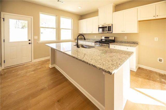 kitchen with sink, white cabinets, a center island with sink, and appliances with stainless steel finishes