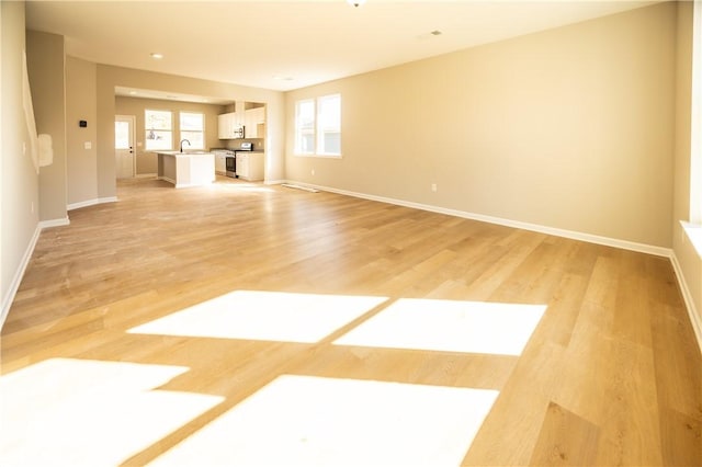 unfurnished living room featuring light wood-type flooring and sink