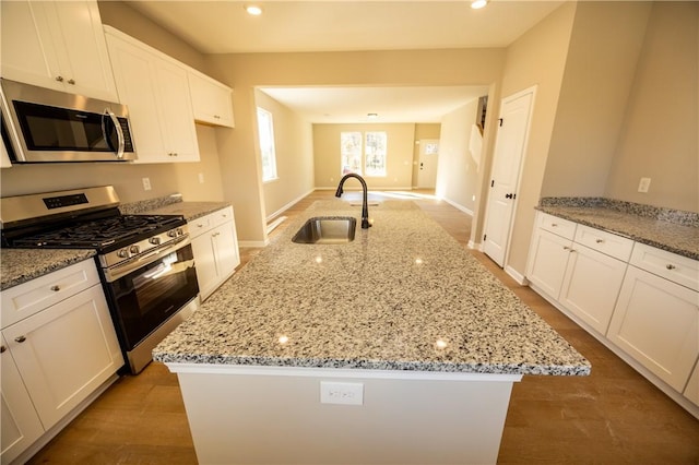 kitchen with white cabinets, sink, an island with sink, and stainless steel appliances