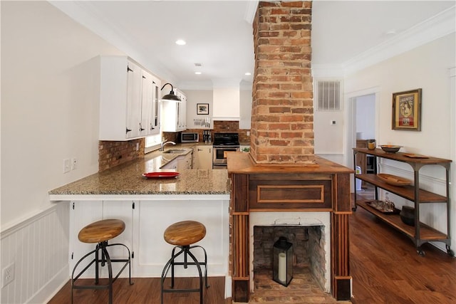kitchen featuring a sink, wainscoting, stainless steel appliances, visible vents, and dark wood-type flooring