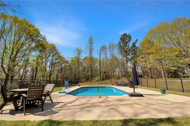 view of swimming pool with a fenced backyard, a fenced in pool, outdoor dining space, and a patio area