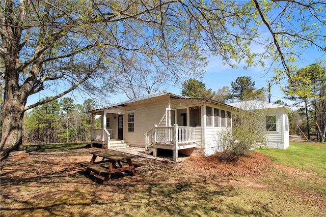 back of property with a lawn and a sunroom