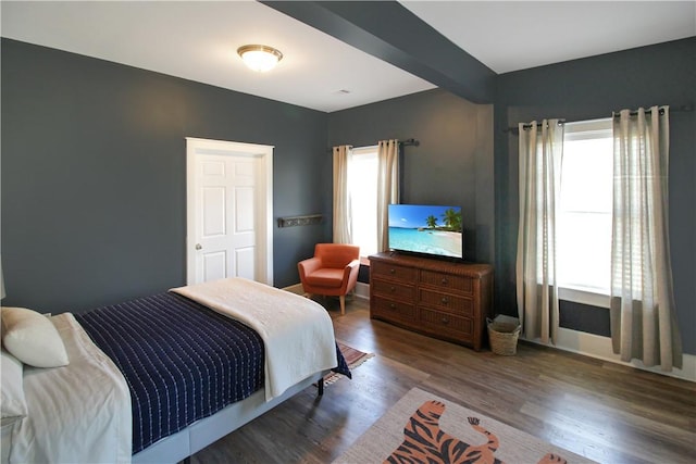 bedroom with beam ceiling and wood finished floors