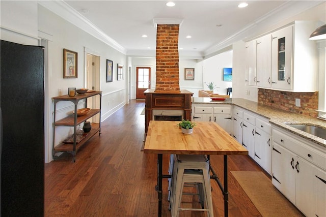 kitchen with decorative columns, backsplash, dark wood-type flooring, white cabinets, and ornamental molding
