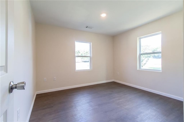 unfurnished room with dark wood-style flooring, baseboards, and visible vents
