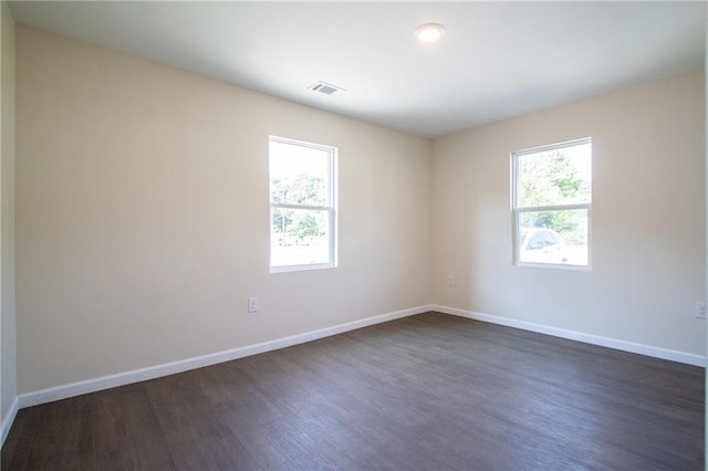 empty room with visible vents, baseboards, and dark wood finished floors