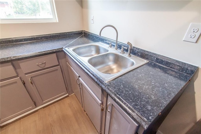kitchen with light wood-type flooring, a sink, and dark countertops
