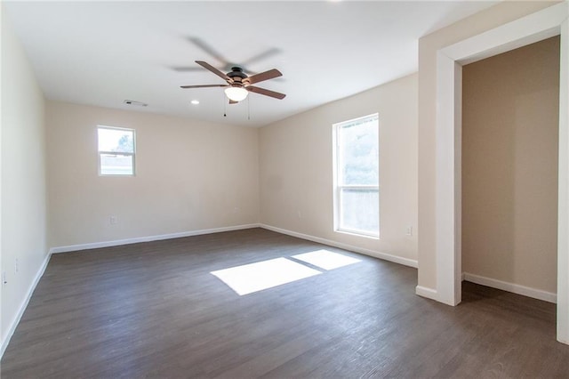 spare room with dark wood-style floors, baseboards, and a ceiling fan