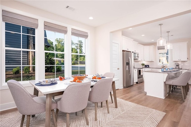 dining room featuring baseboards, light wood-style floors, visible vents, and recessed lighting