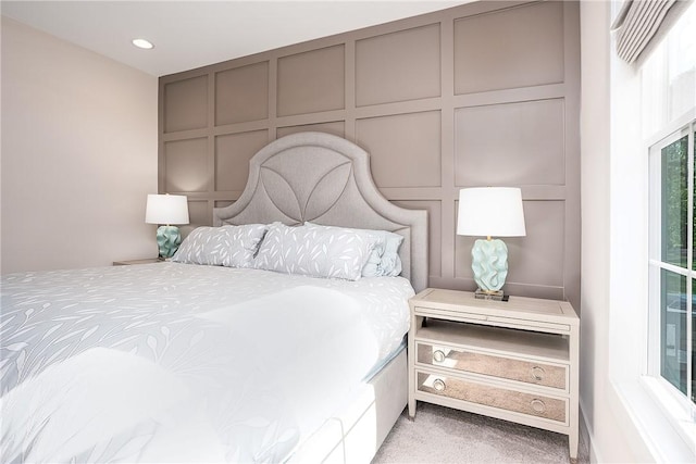 bedroom featuring multiple windows, light carpet, and a decorative wall