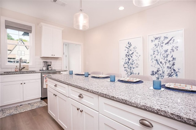 kitchen with stainless steel dishwasher, light stone counters, a sink, dark wood-style flooring, and visible vents