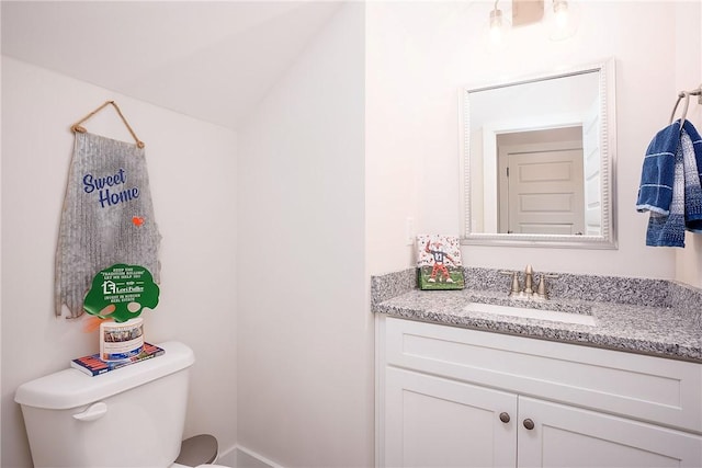 bathroom with toilet, lofted ceiling, and vanity