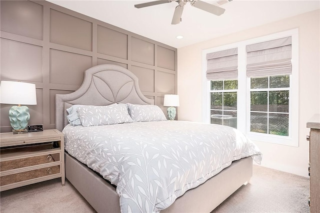 bedroom with light carpet, a ceiling fan, a decorative wall, and recessed lighting