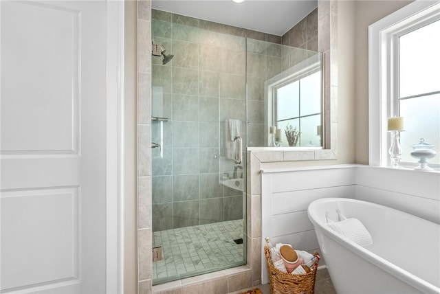 full bathroom with a stall shower, a freestanding tub, and plenty of natural light