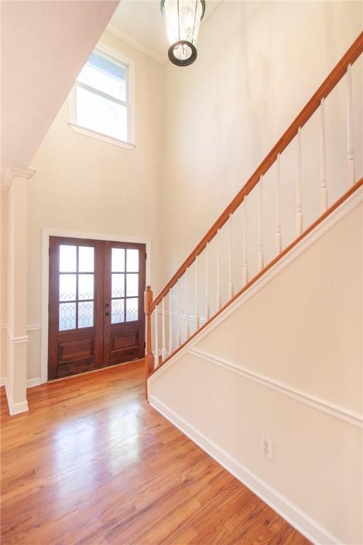 foyer featuring ornamental molding, french doors, light hardwood / wood-style flooring, and plenty of natural light