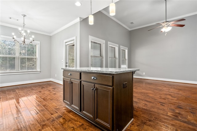 kitchen with hanging light fixtures, crown molding, a kitchen island, and dark wood-type flooring