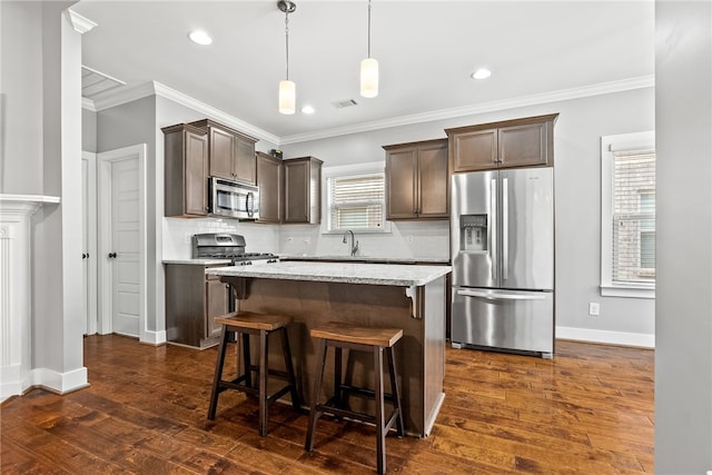 kitchen with sink, decorative backsplash, hanging light fixtures, a center island, and stainless steel appliances