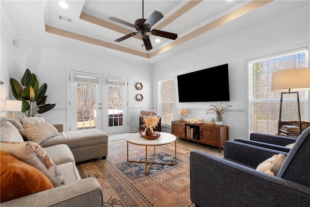 living area with visible vents, crown molding, ceiling fan, french doors, and a raised ceiling