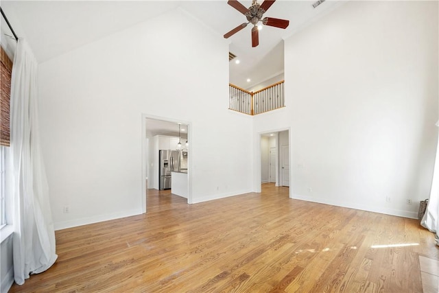 unfurnished living room featuring ceiling fan, high vaulted ceiling, and light wood-type flooring