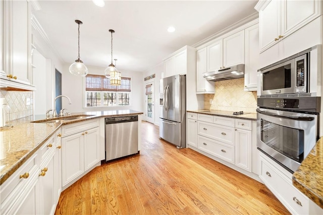 kitchen with sink, white cabinetry, light stone counters, decorative light fixtures, and stainless steel appliances