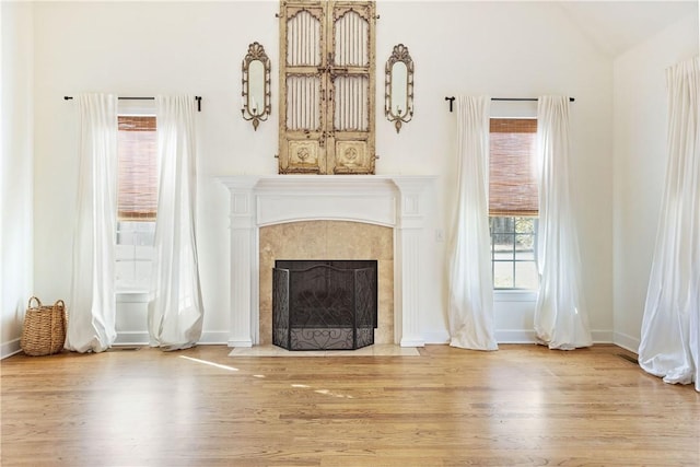 unfurnished living room featuring a tile fireplace, vaulted ceiling, and light hardwood / wood-style flooring