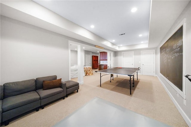 recreation room with a tray ceiling and light colored carpet