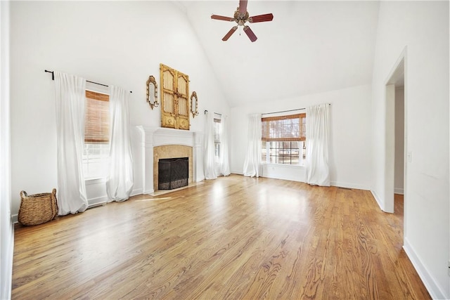 unfurnished living room with ceiling fan, high vaulted ceiling, a fireplace, and light hardwood / wood-style flooring