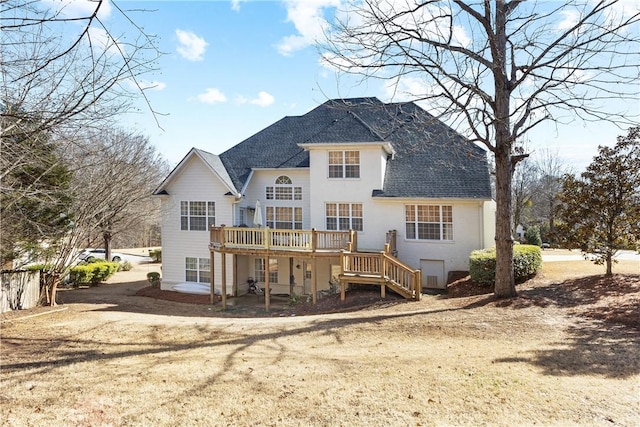 rear view of property featuring a wooden deck and a lawn