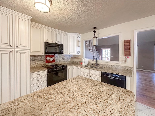 kitchen featuring black appliances, sink, light stone countertops, tasteful backsplash, and decorative light fixtures