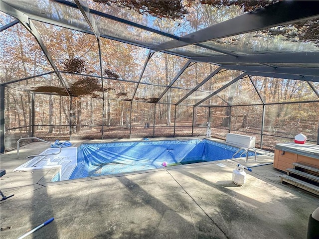 view of pool featuring glass enclosure, a patio, and a hot tub