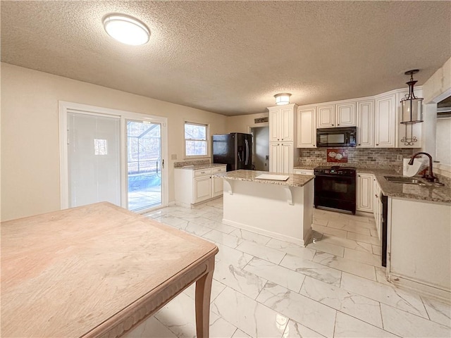 kitchen with light stone countertops, sink, black appliances, pendant lighting, and a center island