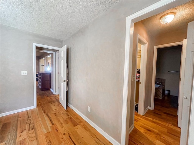 hallway featuring light hardwood / wood-style floors and a textured ceiling