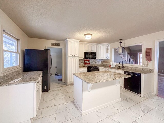 kitchen with white cabinetry, a textured ceiling, a breakfast bar, a kitchen island, and black appliances