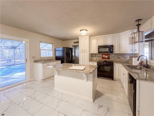 kitchen featuring light stone countertops, sink, black appliances, decorative light fixtures, and white cabinets