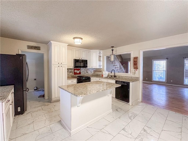 kitchen with white cabinetry, a center island, sink, decorative light fixtures, and black appliances