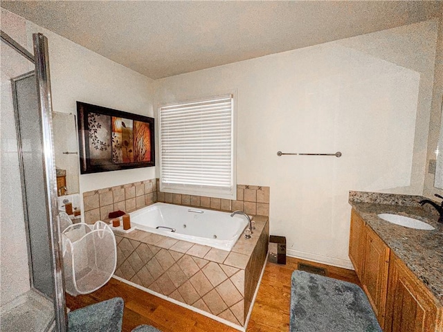 bathroom featuring vanity, shower with separate bathtub, a textured ceiling, and hardwood / wood-style floors