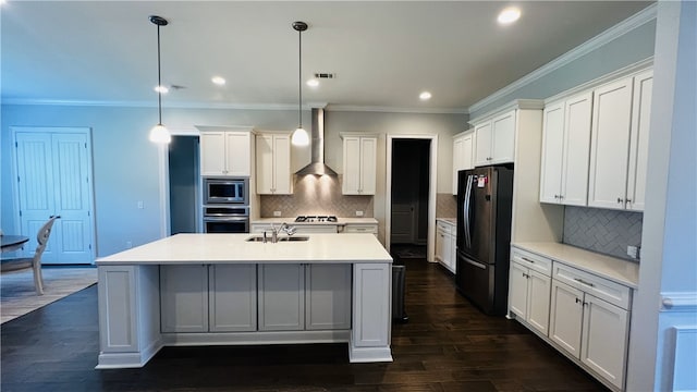 kitchen featuring sink, wall chimney exhaust hood, tasteful backsplash, decorative light fixtures, and appliances with stainless steel finishes