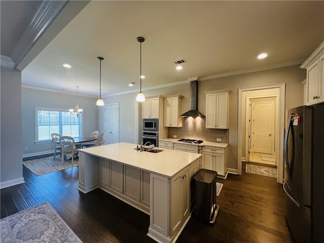 kitchen featuring wall chimney exhaust hood, dark hardwood / wood-style floors, an island with sink, decorative light fixtures, and appliances with stainless steel finishes