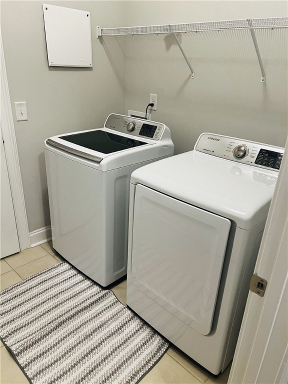 laundry area with independent washer and dryer and light tile patterned flooring