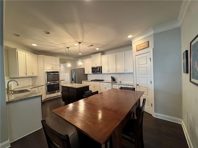 kitchen featuring ornamental molding, stainless steel appliances, dark wood-type flooring, a center island, and a sink