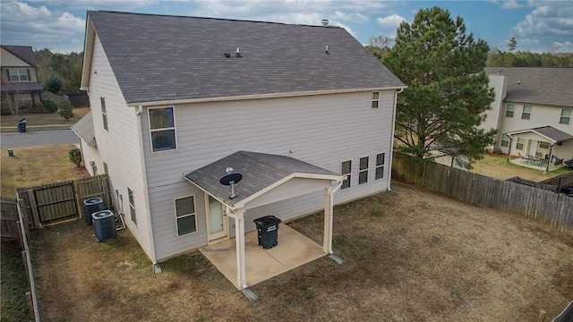 rear view of house featuring central AC unit, roof with shingles, a patio area, and a fenced backyard