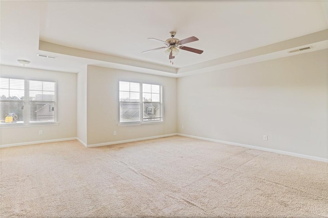 empty room featuring light carpet, a raised ceiling, and visible vents